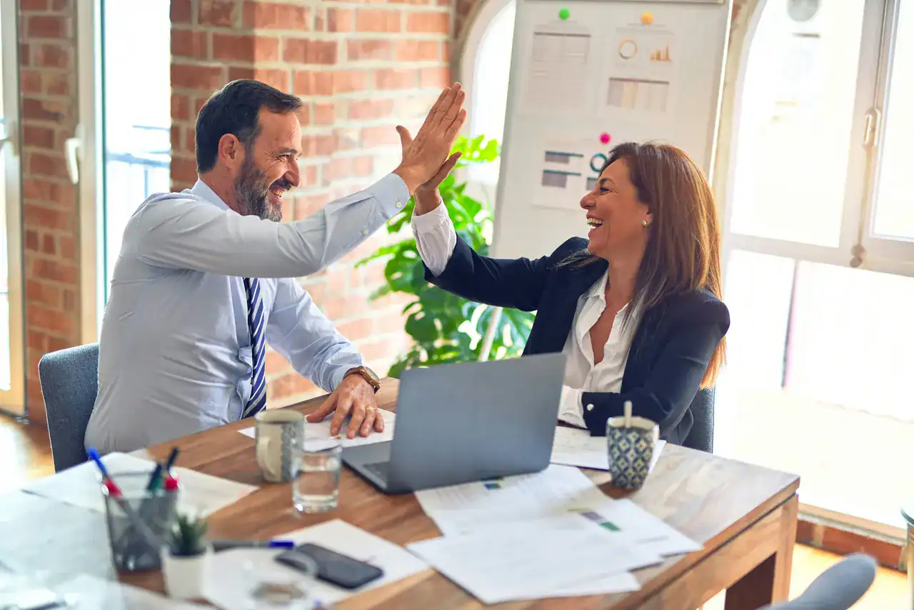 Business professionals high-fiving during a successful financial or project review.